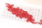 a clear ruler with red floral embroidery or lace appliqués placed on it.