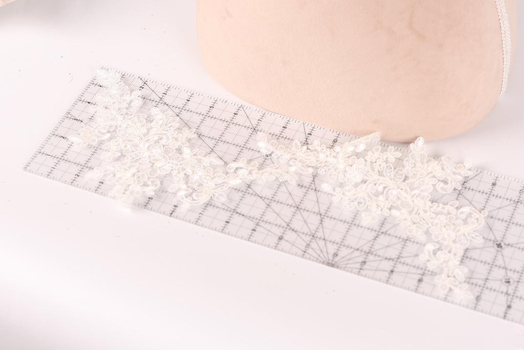 a close-up view of a piece of lace with a grid pattern on it, placed on a ruler.