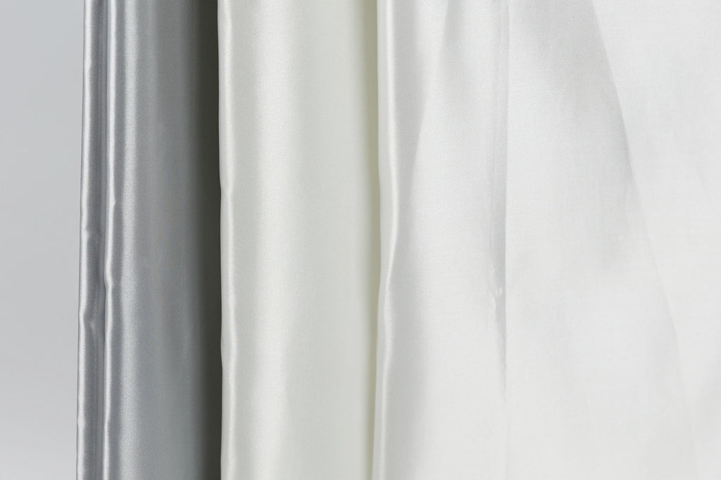 a close-up view of three fabric swatches, with the middle one being white and the other two being gray.