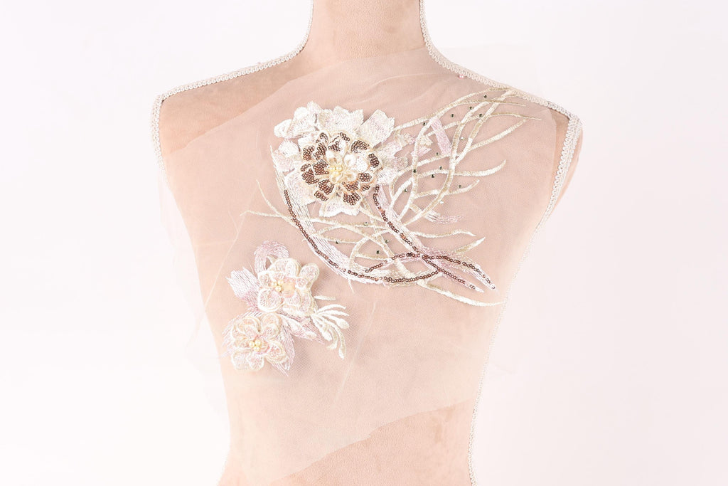 A mannequin with a delicate, intricate floral embroidery on its shoulder.