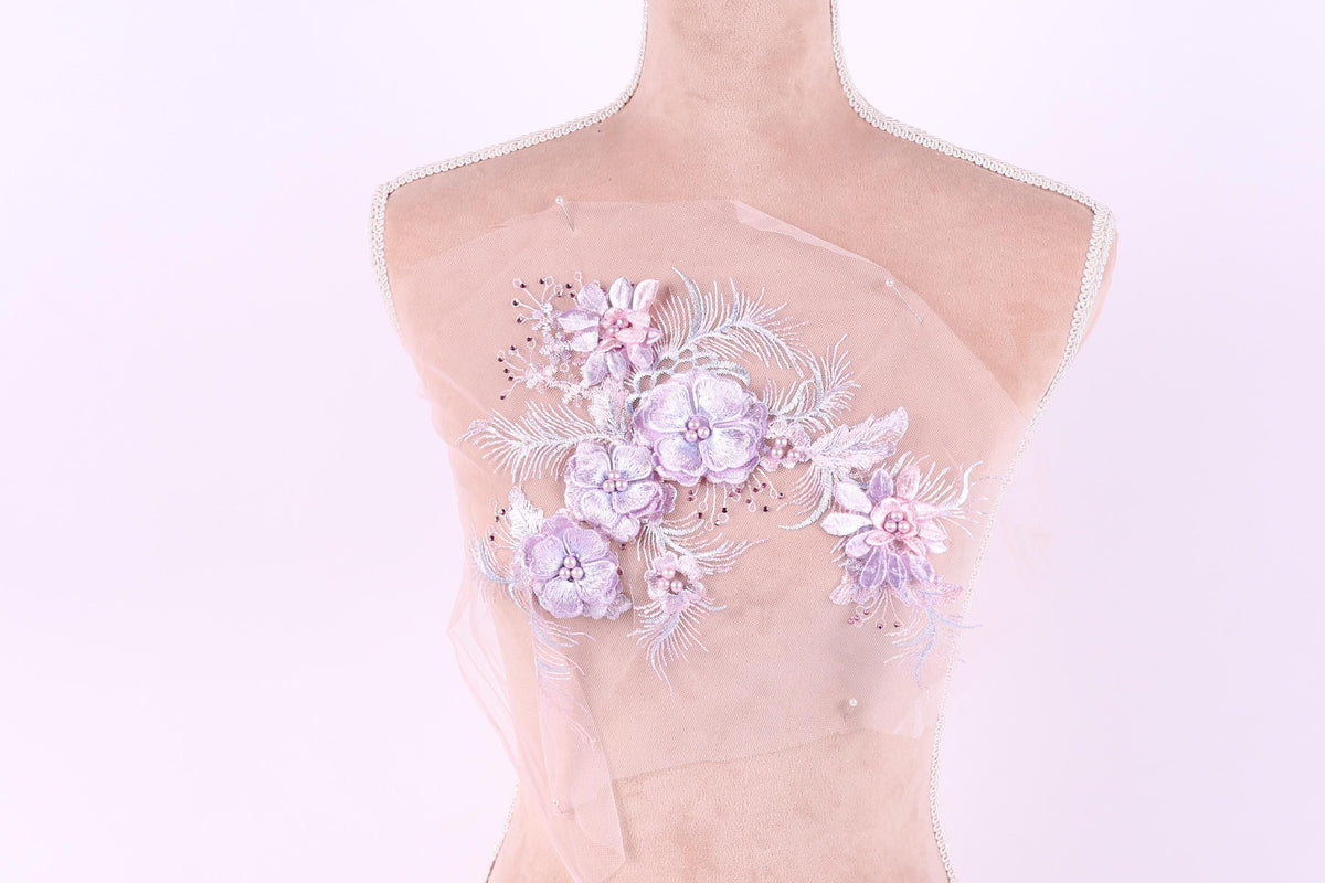 A mannequin with a delicate floral embroidered on its chest against a light pink background.