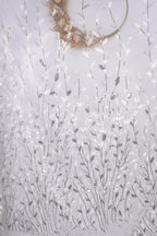 a white fabric with a repeating pattern of silver and white leaves and flowers, creating a delicate and intricate design.
