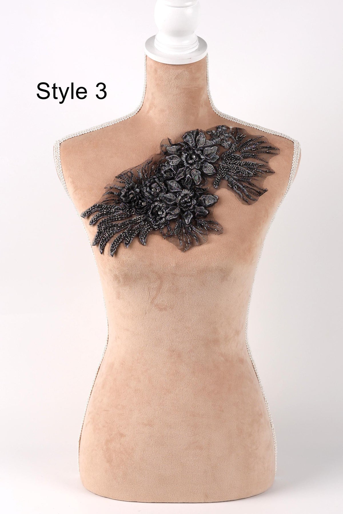 A mannequin with a decorative black floral embellishment on its chest.