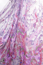 a close-up view of a fabric with a vibrant, multicolored floral pattern. The fabric appears to be made of a sheer material, with a mix of pink, purple, and green colors. The pattern is intricate and detailed, showcasing the craftsmanship and artistry of the fabric design.