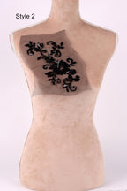 A mannequin with a floral pattern on its back, featuring black sequins or beads.