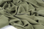 a close-up view of a crumpled, olive green fabric, with its folds and creases clearly visible.
