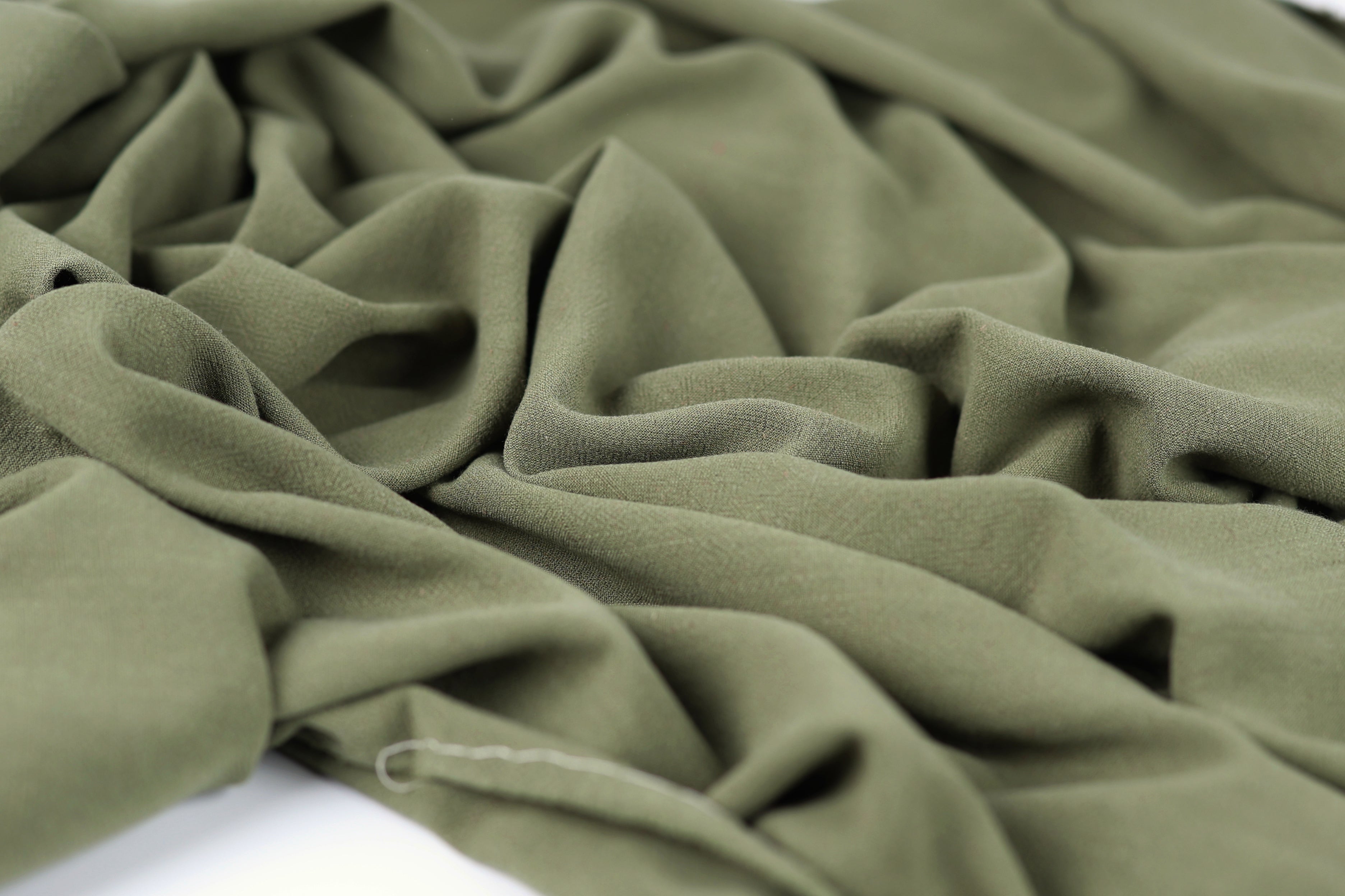 a close-up view of a crumpled, olive green fabric, with its folds and creases clearly visible.