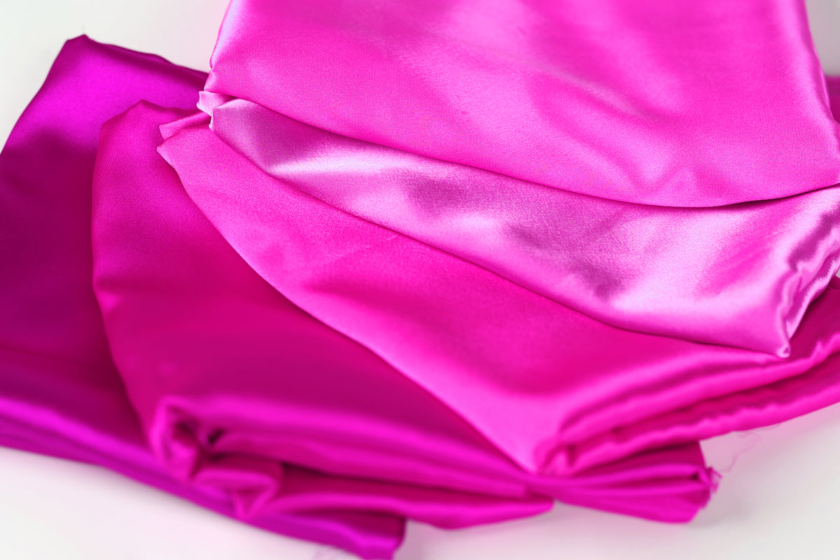 a close-up view of several pieces of pink satin fabric, with varying degrees of wrinkled texture.