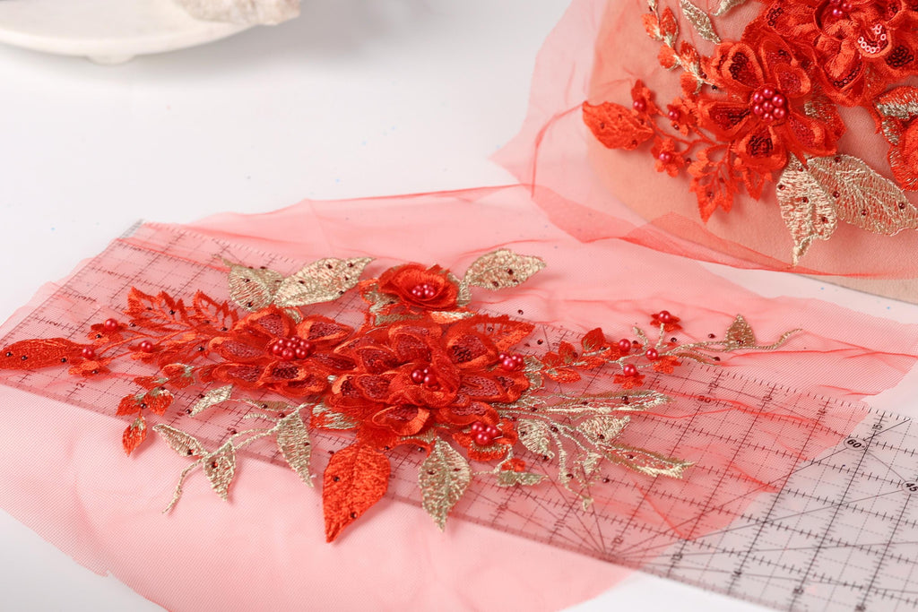 a close-up view of a red floral embroidery on a pink background.