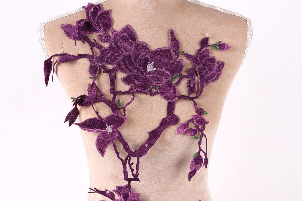 a mannequin with a back adorned with a floral design in shades of purple. The design consists of purple flowers and leaves, creating a visually striking and intricate pattern.