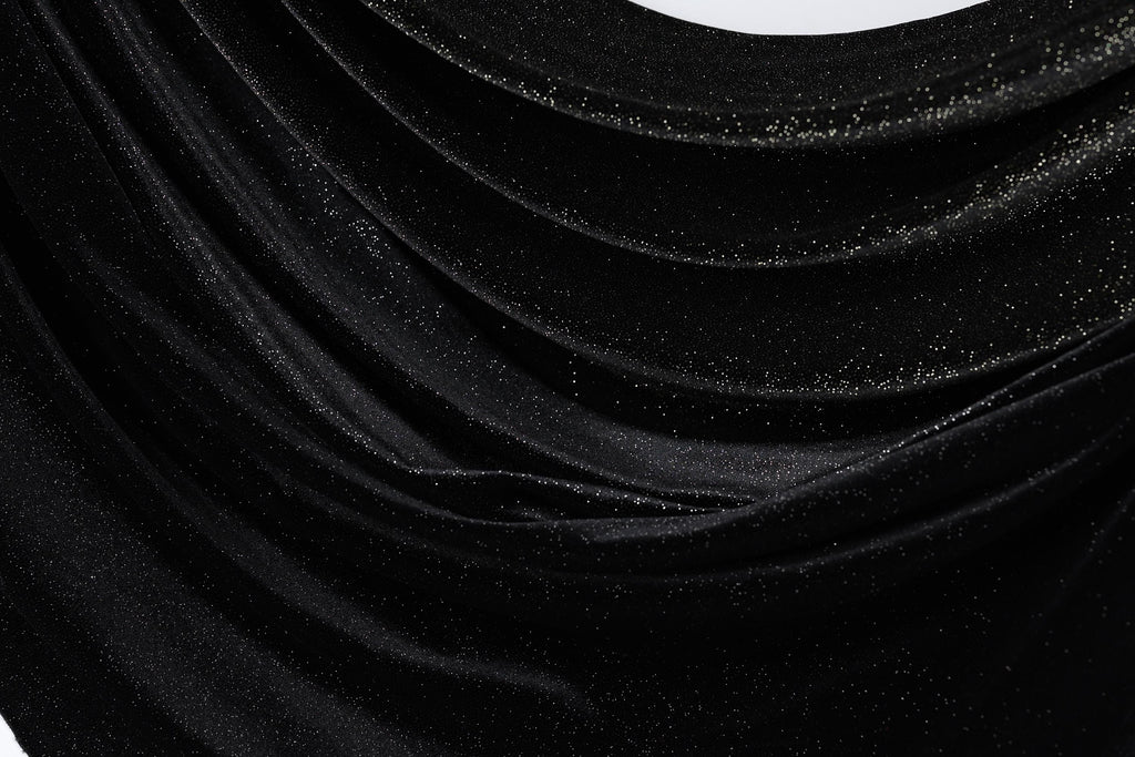The image is a close-up of a shiny black fabric with a sparkling texture, creating a visually striking contrast.