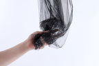 A hand is holding a black, shiny, and textured fabric or material, which appears to be a piece of clothing or textile.