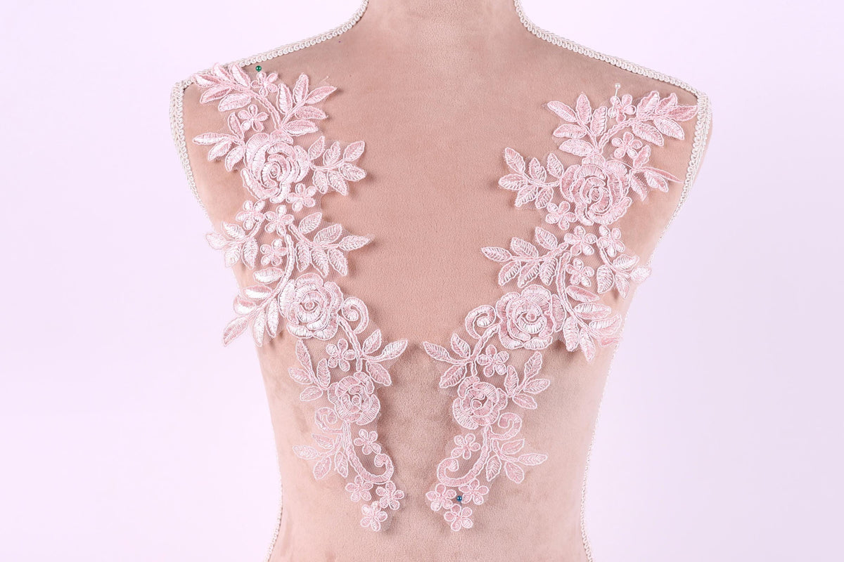 A mannequin with a pink floral lace design on its shoulders.
