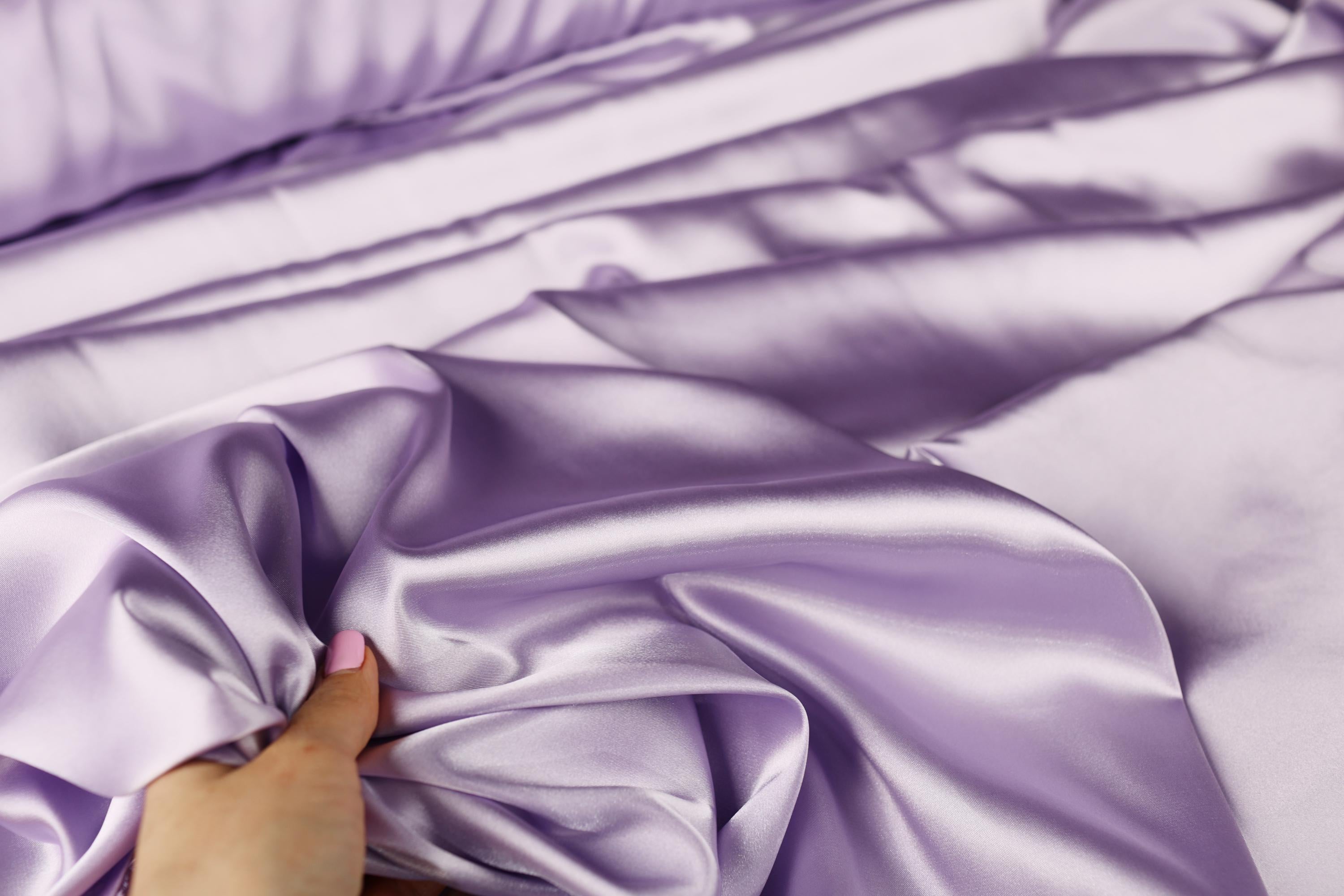 a person is laying on a bed with a purple comforter