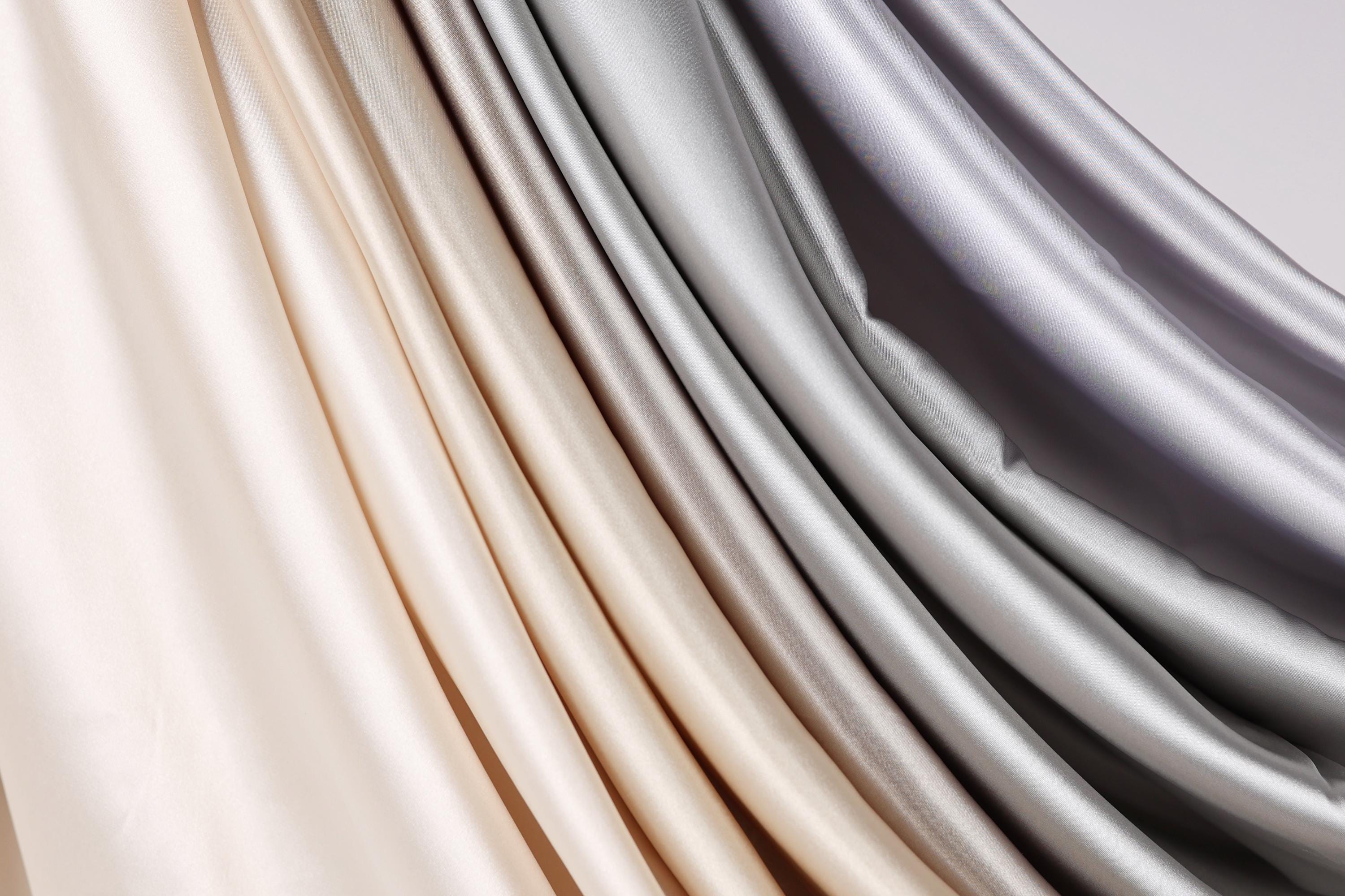 a close-up view of a fabric with a gradient of colors, transitioning from light to dark shades of gray and beige.