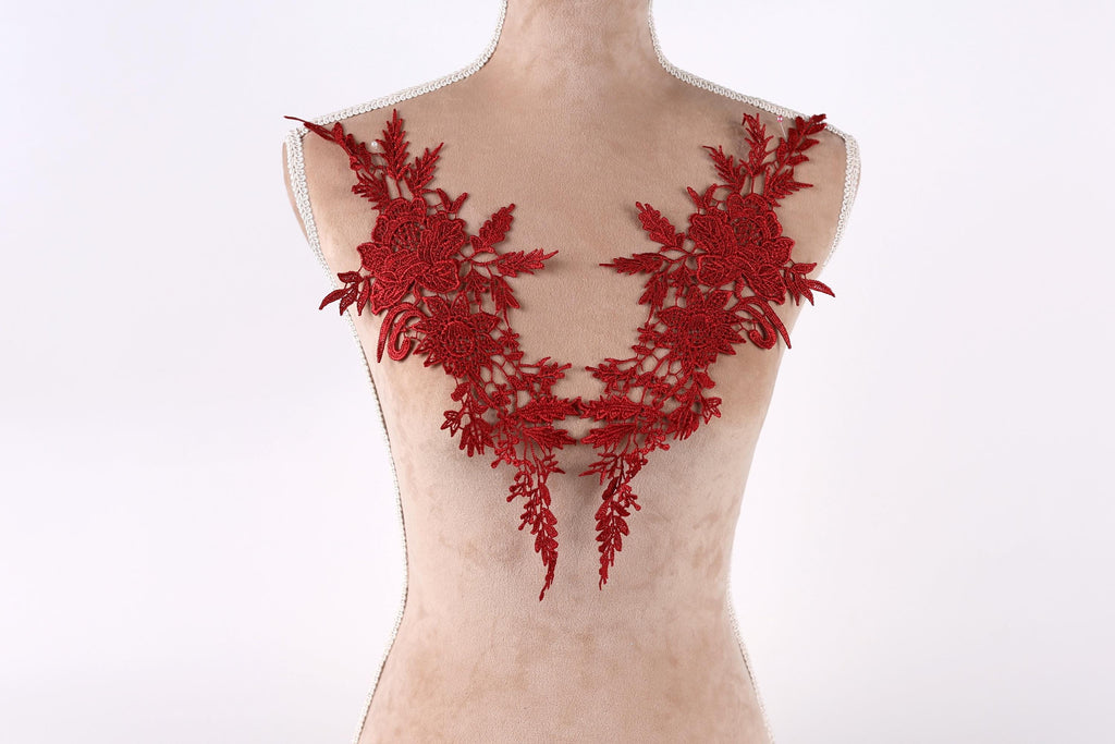 A mannequin torso wearing a red lace dress with intricate floral embroidery.