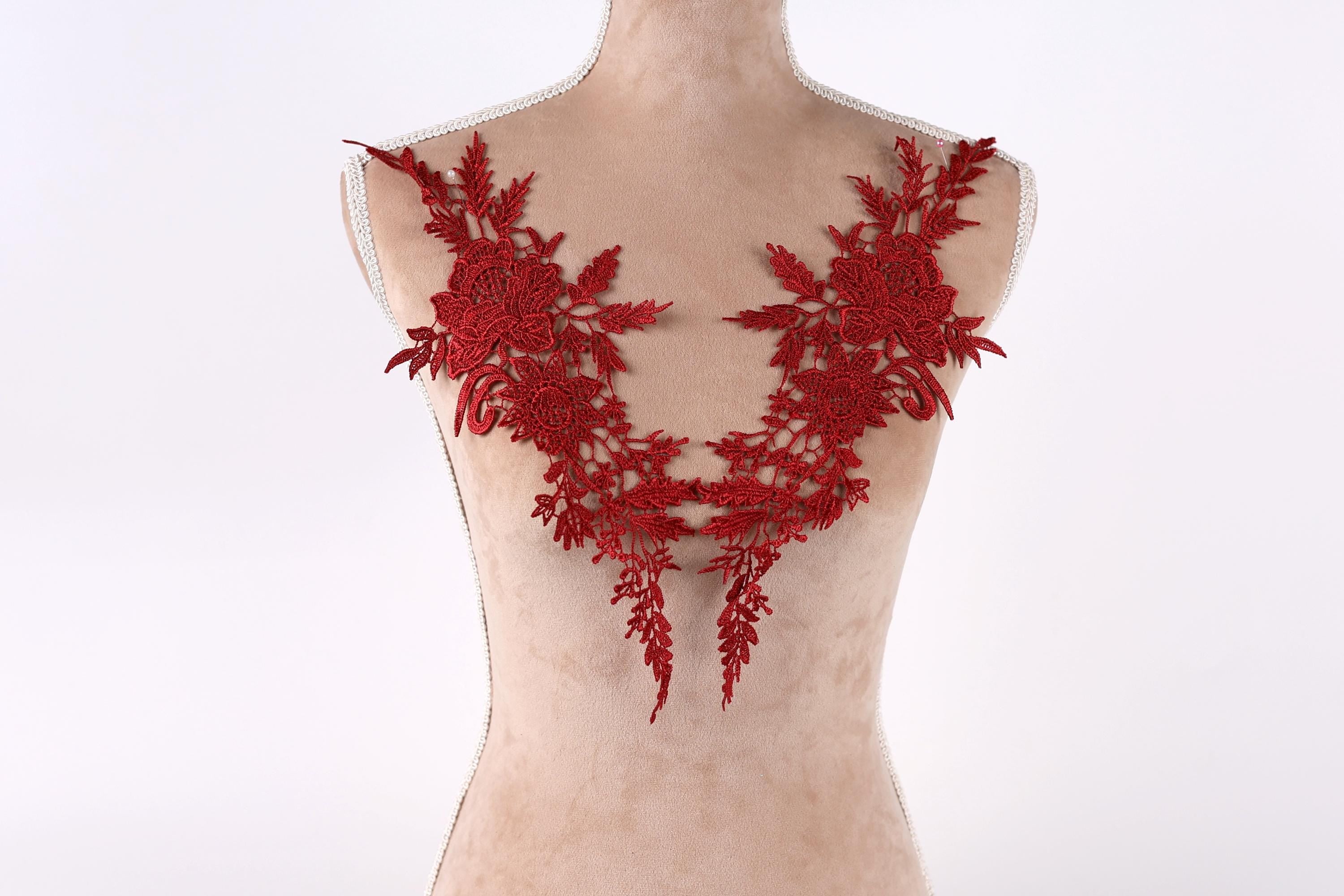 A mannequin torso wearing a red lace dress with intricate floral embroidery.