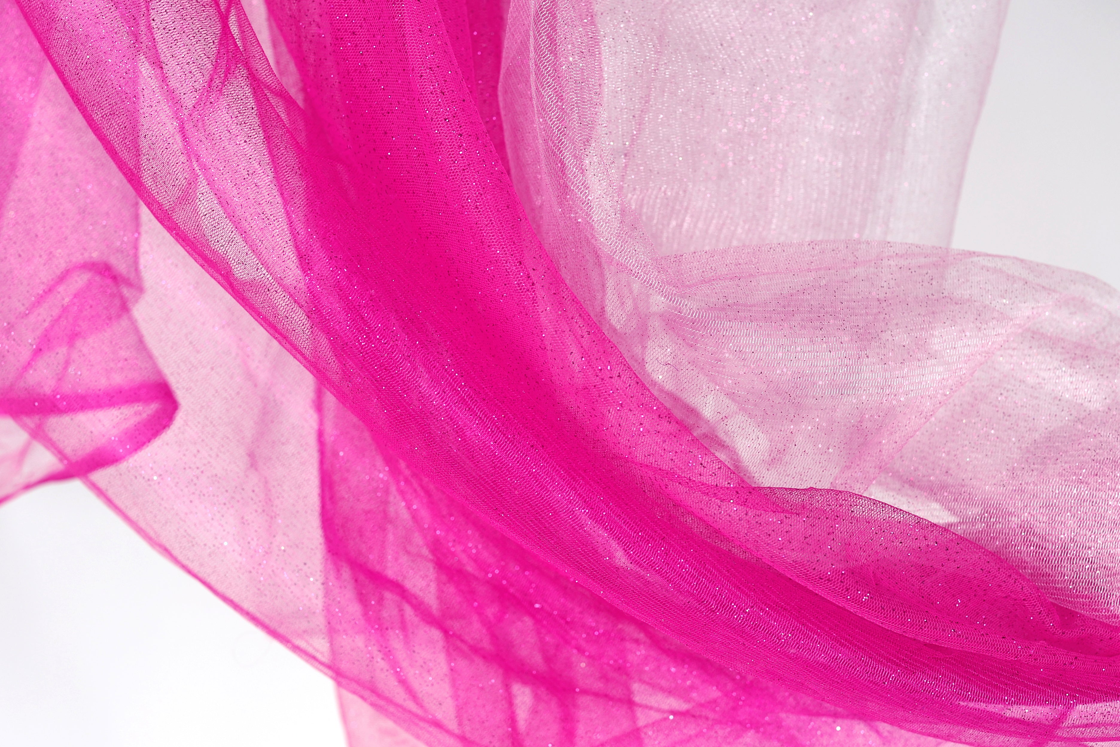 The image is a close-up of a pink fabric with a shiny, sparkly texture.