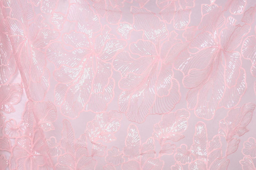 a close-up view of a fabric with a delicate, intricate floral pattern in shades of pink and white. The pattern consists of numerous small, overlapping flowers and leaves, creating a visually appealing and delicate design. The fabric appears to be made of a soft, delicate material, suitable for use in clothing or other textile applications.