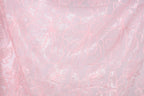 a close-up view of a fabric with a delicate, intricate floral pattern in shades of pink and white. The pattern consists of numerous small, overlapping flowers and leaves, creating a visually appealing and delicate design. The fabric appears to be made of a soft, delicate material, suitable for use in clothing or other textile applications.
