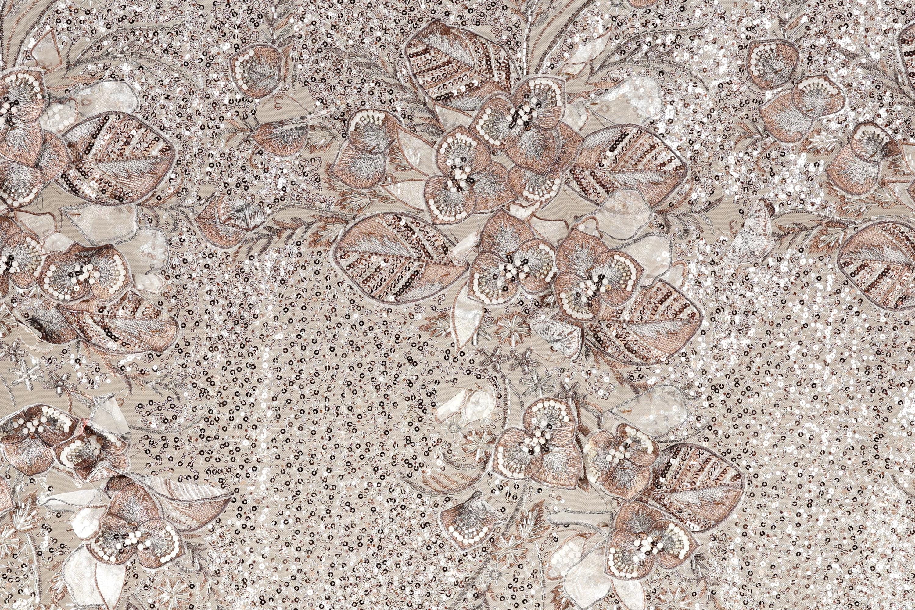 a close-up view of a fabric with a floral pattern. The fabric appears to be made of a material with a beige or brown color, and it has a textured appearance. The pattern consists of various flowers and leaves, some of which are intricately detailed, creating a visually appealing and detailed design.