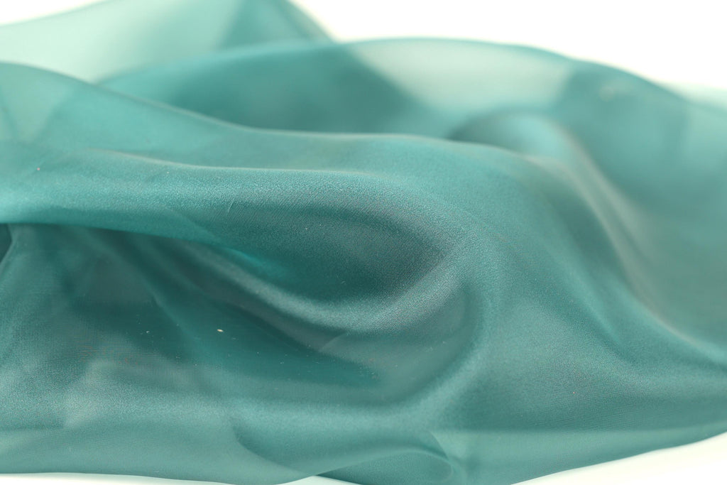 a close-up view of a fabric with a smooth, shiny texture in a light blue-green color.