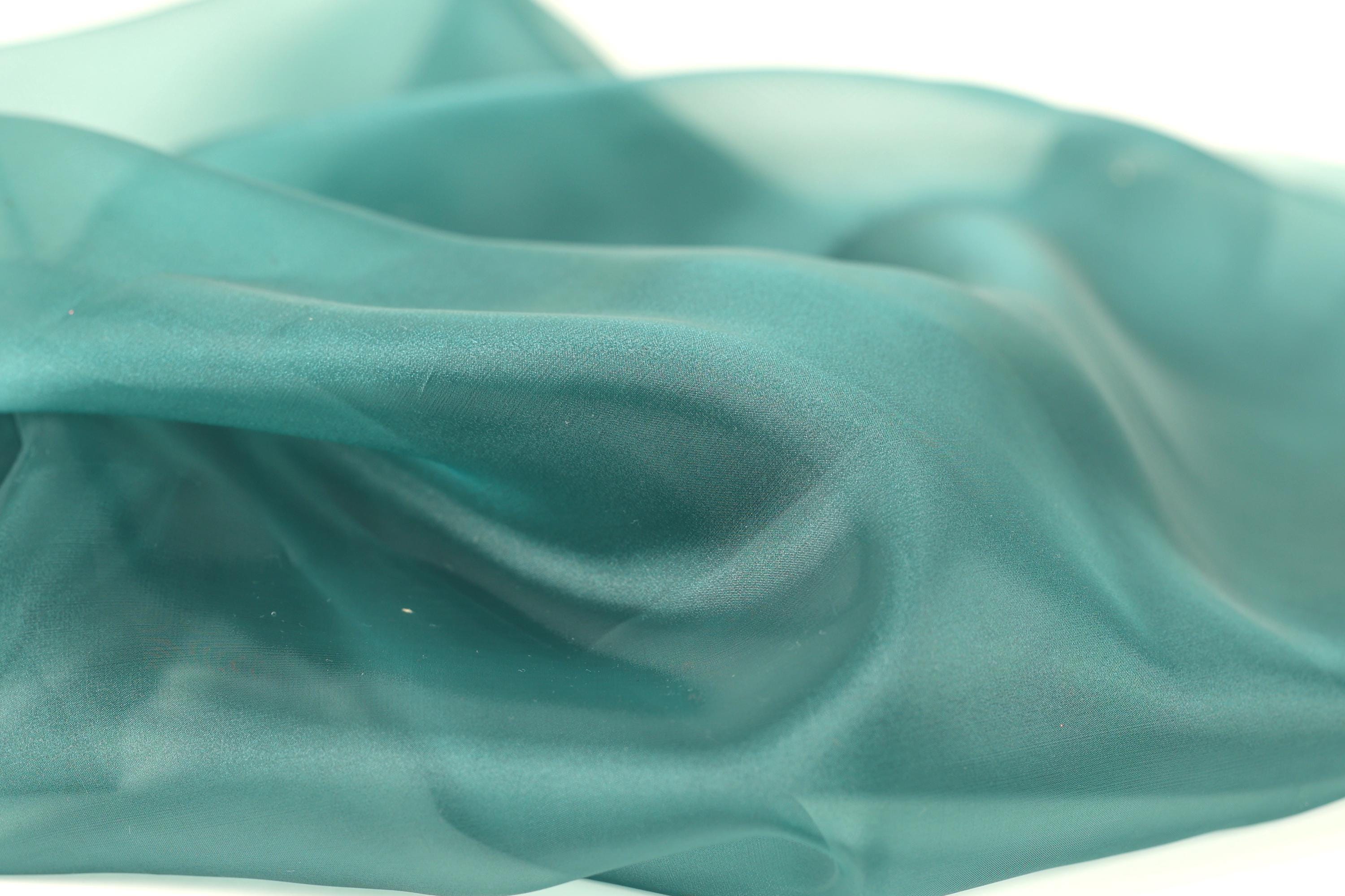 a close-up view of a fabric with a smooth, shiny texture in a light blue-green color.