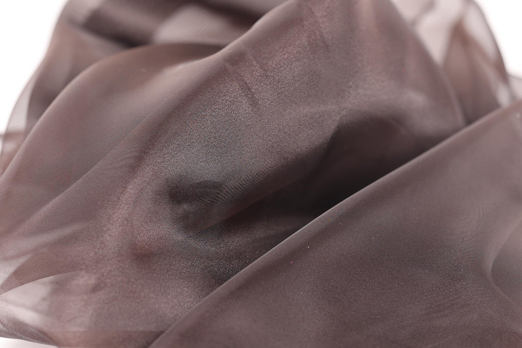 a close-up view of a brown, shiny fabric, possibly silk or chiffon, with a textured and wrinkled appearance.