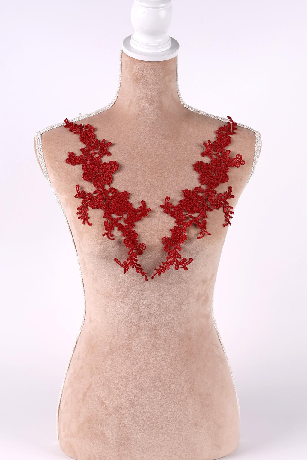 A mannequin wearing a red lace dress with a floral pattern on the shoulders.