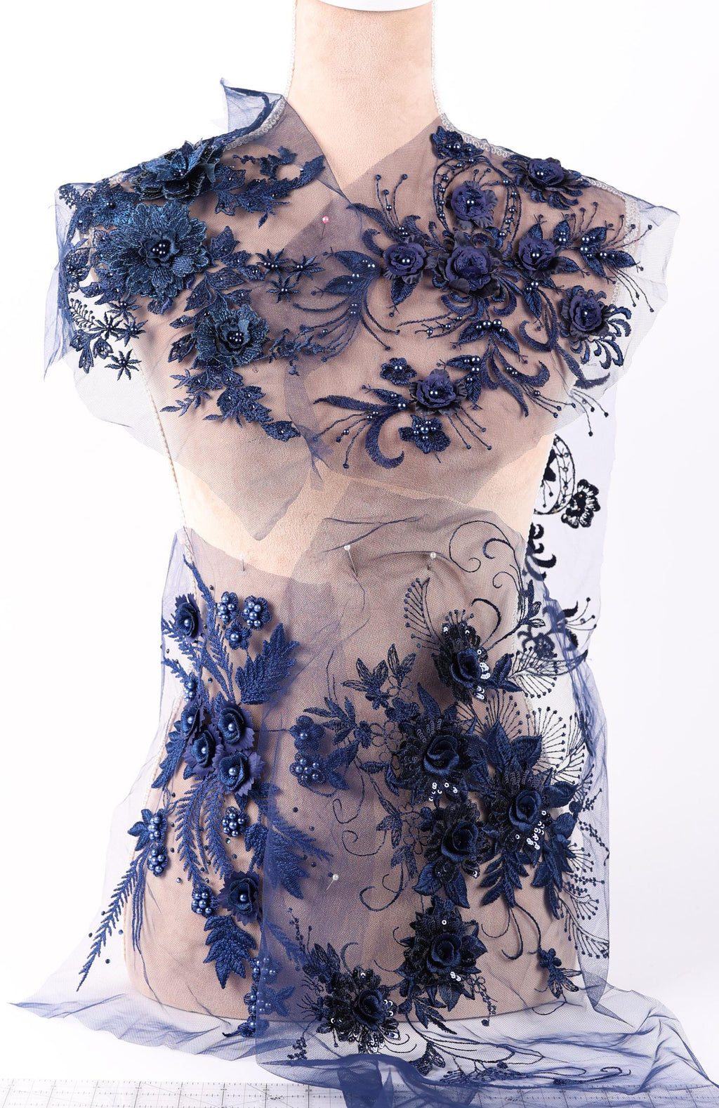 A mannequin wearing a dress with a floral pattern in shades of blue, including blue flowers, leaves, and other decorative elements.