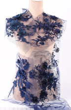 A mannequin wearing a dress with a floral pattern in shades of blue, including blue flowers, leaves, and other decorative elements.