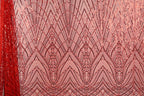a close-up view of a fabric with a repeating pattern of red and pink sequin designs. The pattern consists of a series of diamond shapes and lines, creating a visually striking and intricate design. The fabric appears to be a sheer material, with the sequins adding a touch of sparkle and texture to the overall appearance.
