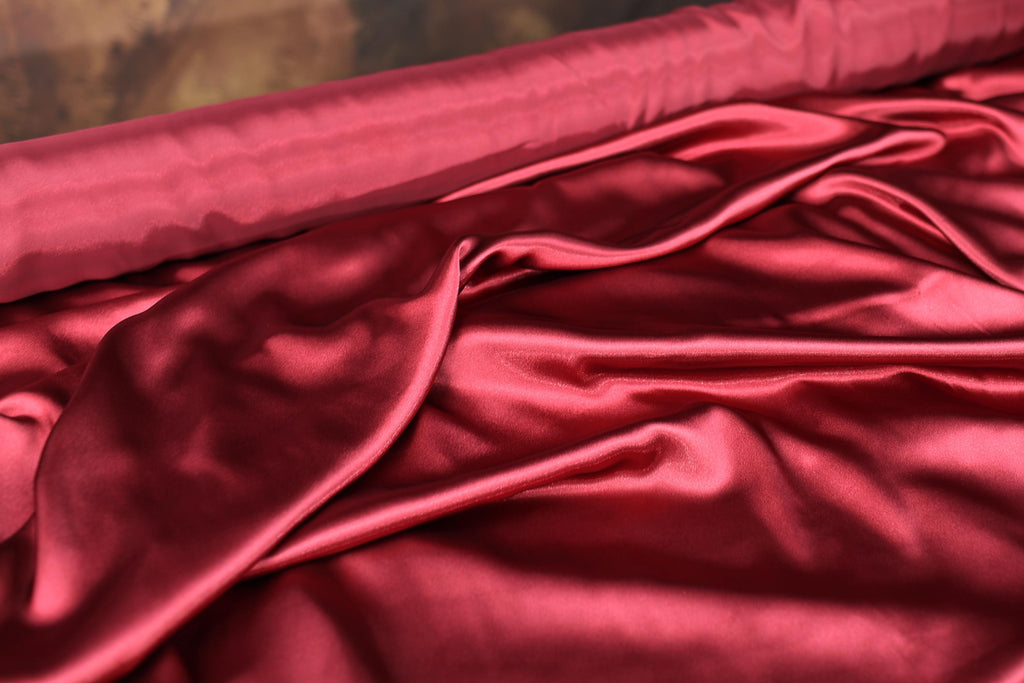a close up of a red cloth on a bed