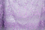 a fabric with a repeating pattern of purple flowers and leaves, creating a visually appealing and intricate design.
