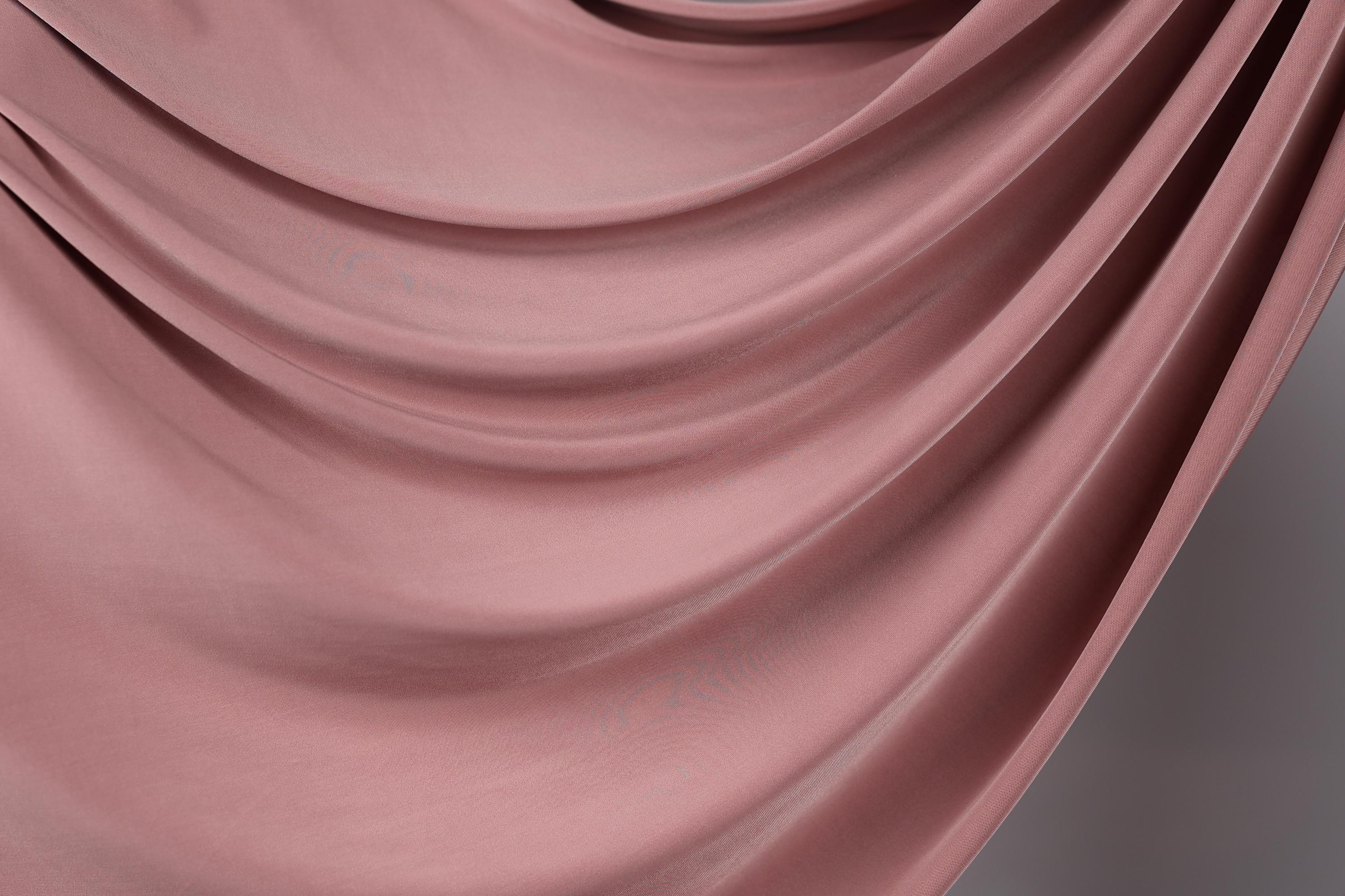 a close-up view of a soft, flowing pink fabric, possibly a satin or velvet material. The fabric appears to be draped or swirled, creating a sense of movement and elegance.