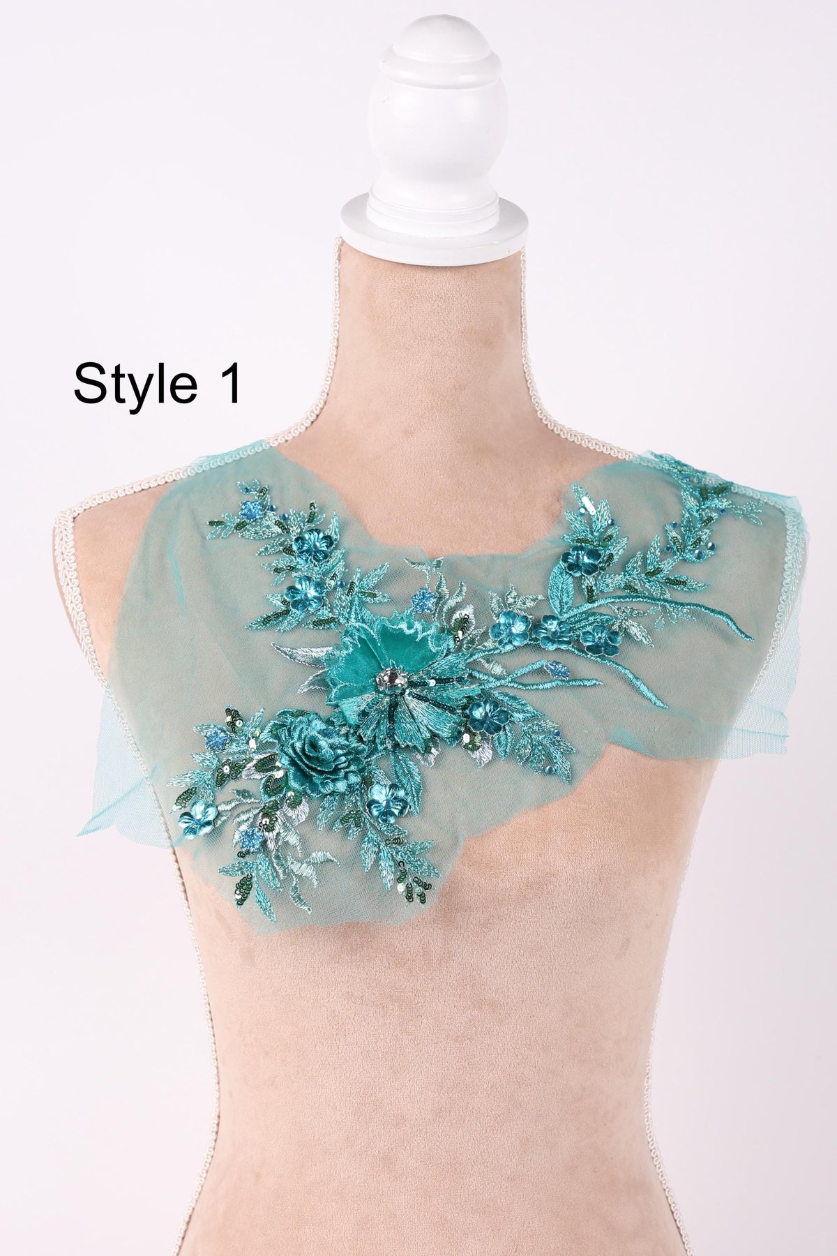 A mannequin wearing a light blue floral embroidered patch on its shoulder.