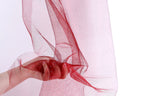 A hand is holding a red, shiny fabric with a delicate, flowing texture.
