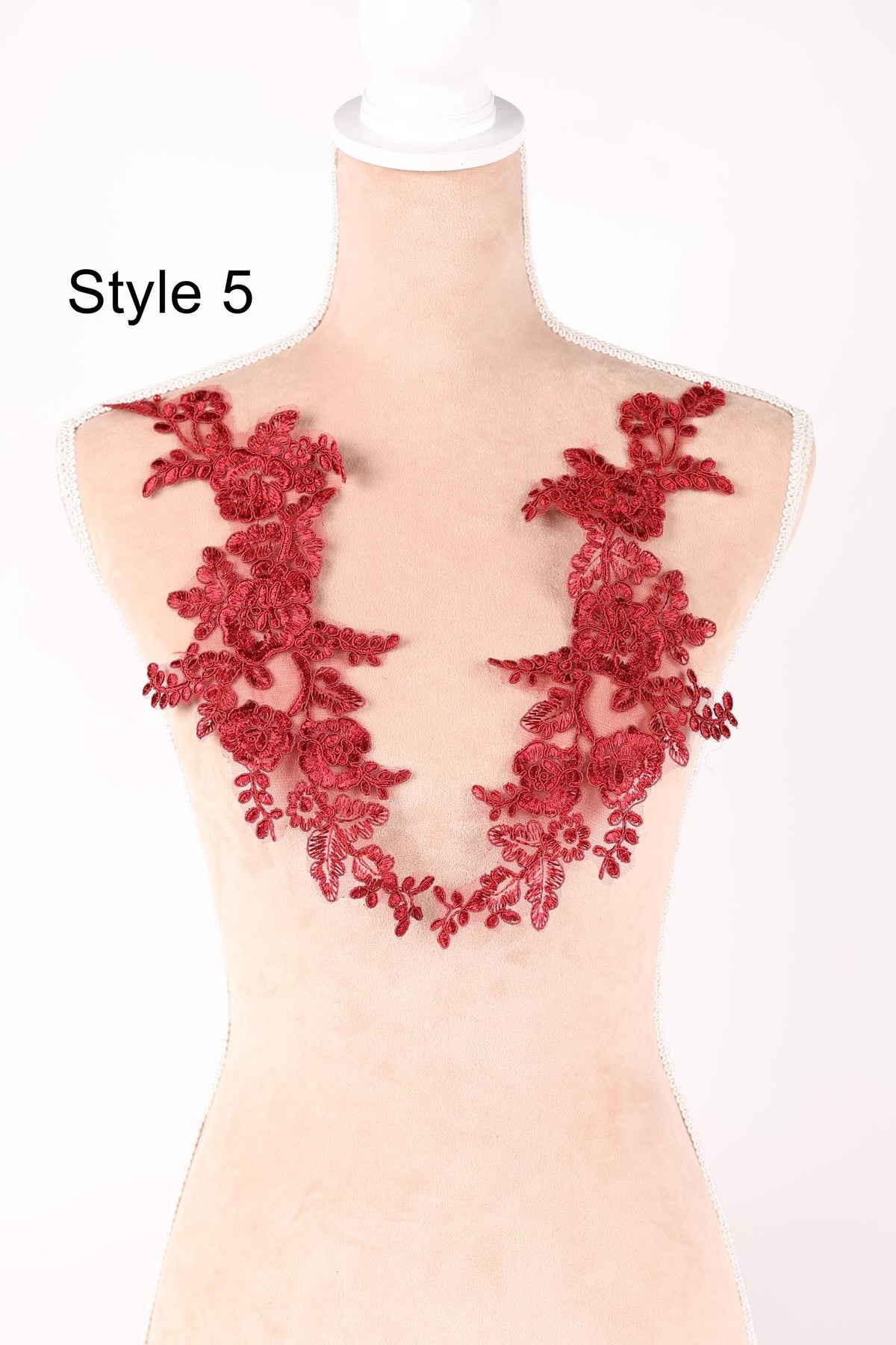 A mannequin wearing a red lace dress with a floral pattern on the bust area.