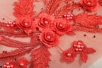 a close-up view of a delicate, intricate red embroidered design with small flowers and beads.