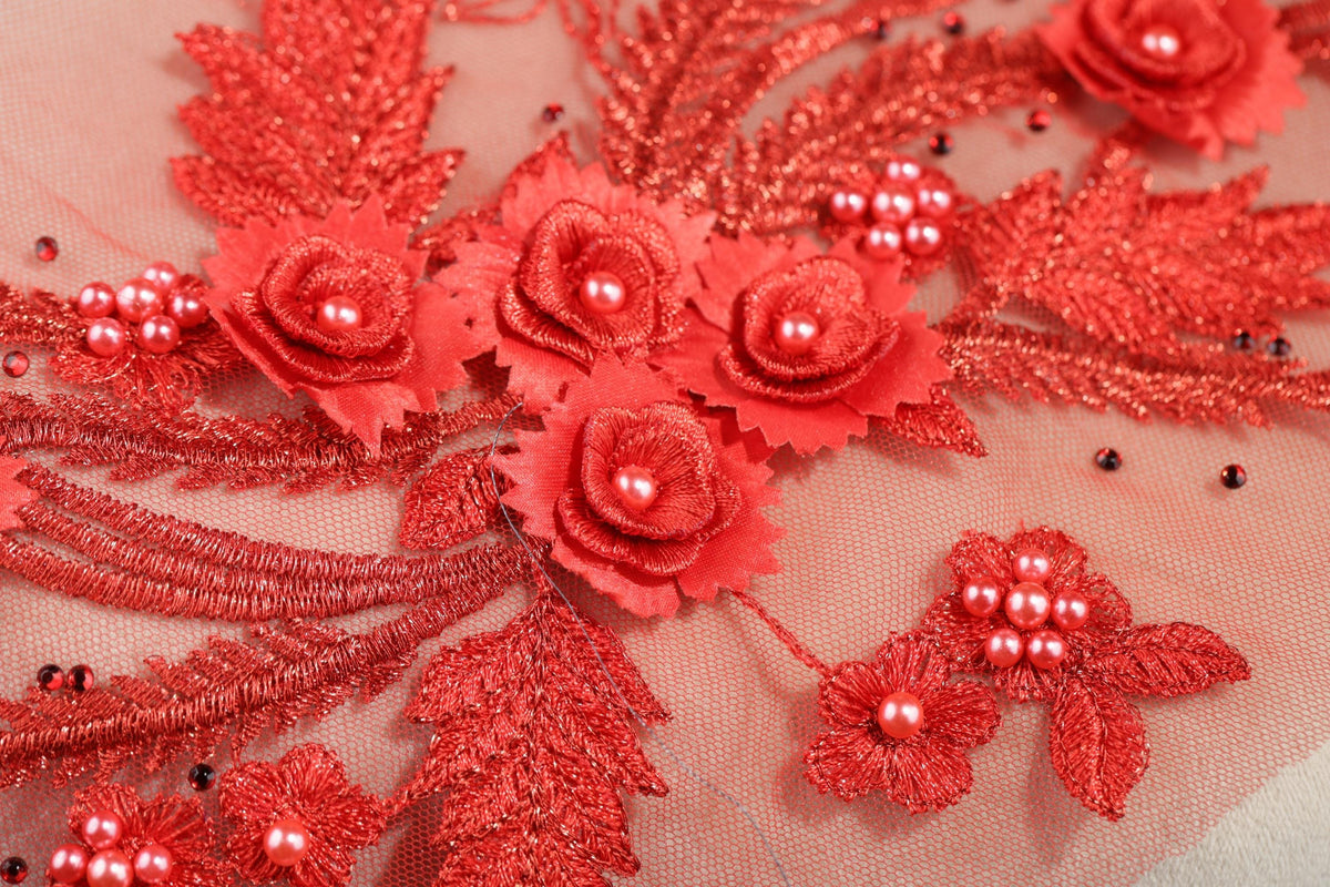a close-up view of a delicate, intricate red embroidered design with small flowers and beads.