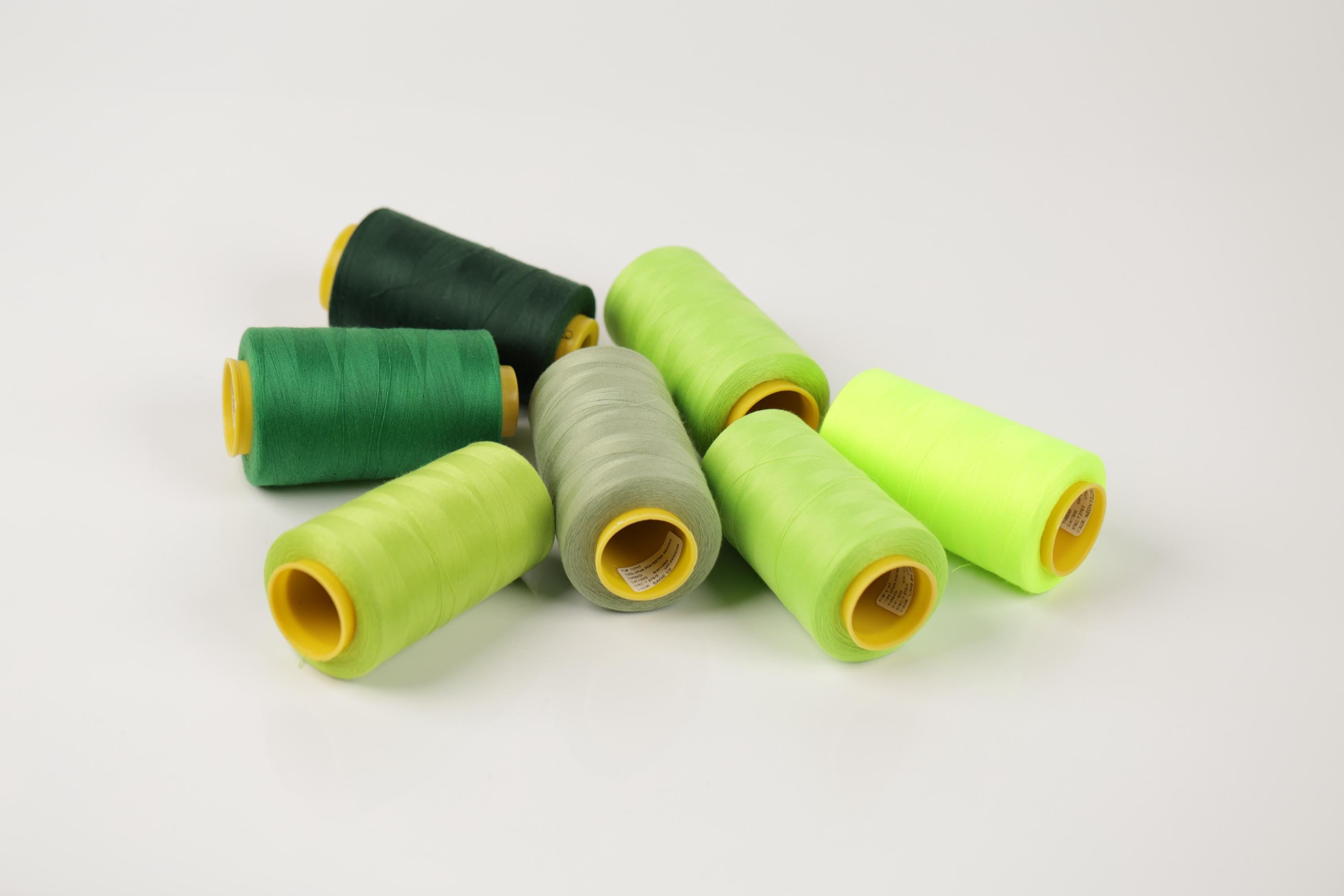 a collection of green and yellow thread spools arranged on a white background.