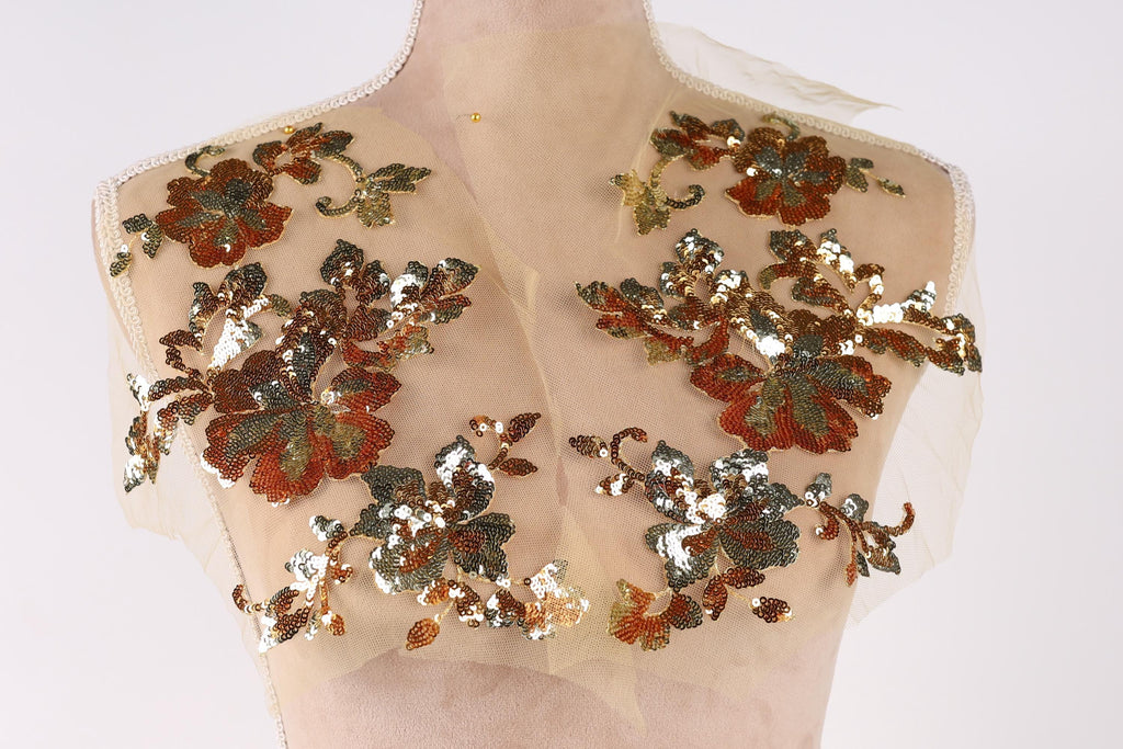 A mannequin with a beige dress and a sheer, floral-patterned fabric covering the upper body.