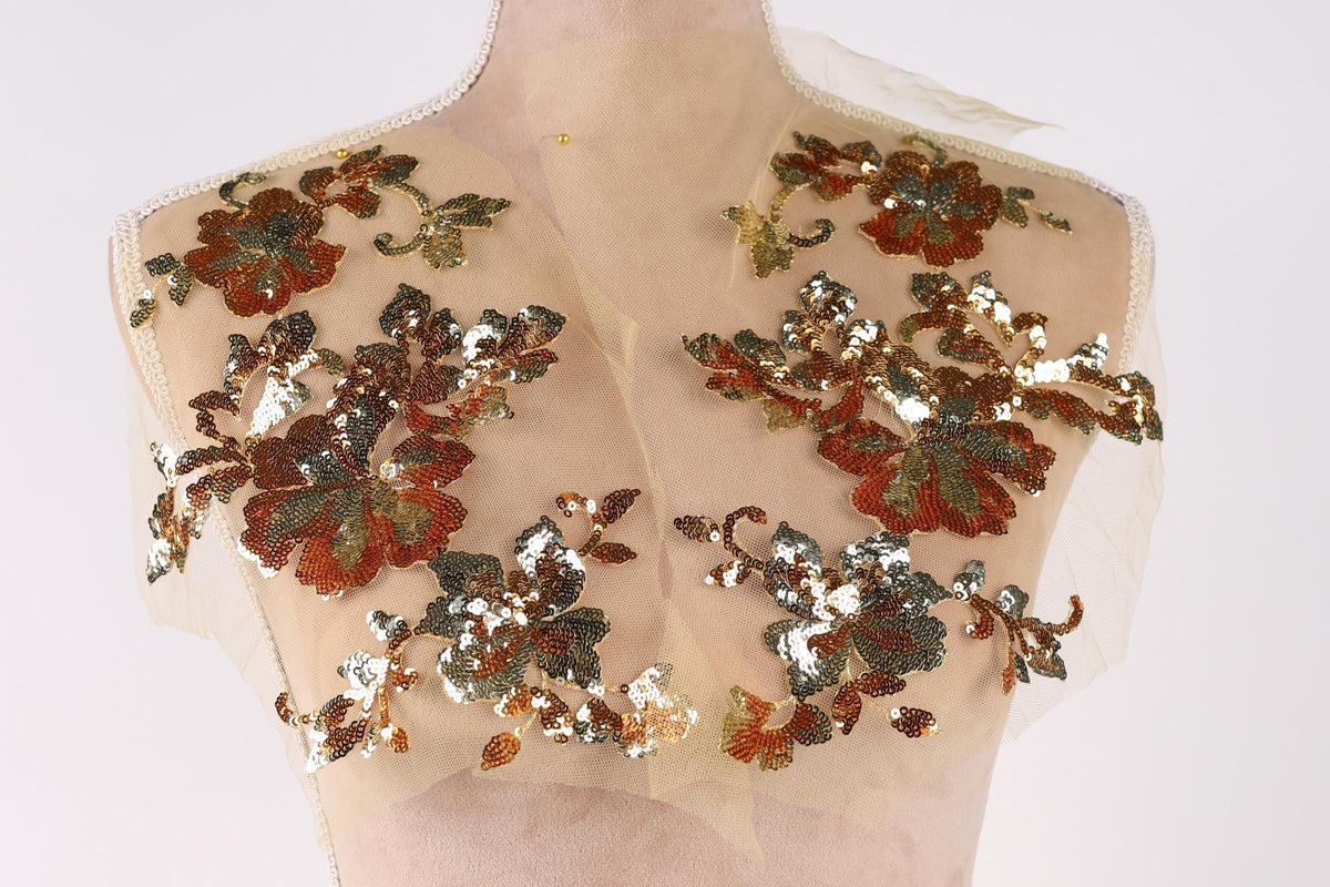 A mannequin with a beige dress and a sheer, floral-patterned fabric covering the upper body.