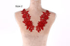 A mannequin wearing a red floral necklace with multiple flower-shaped pieces.