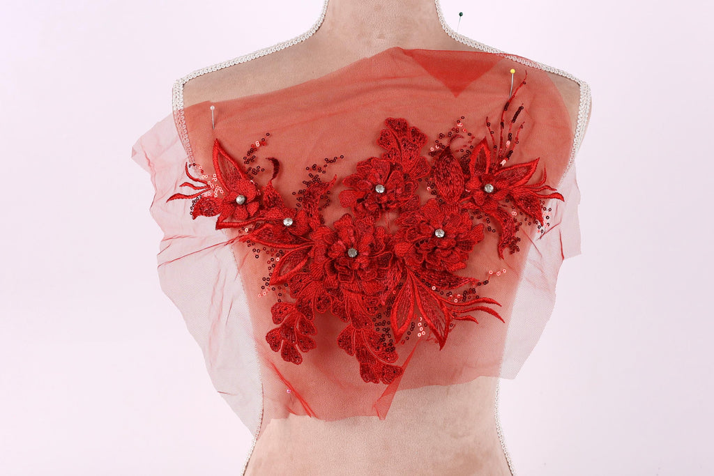 A mannequin wearing a red floral lace overlay on its chest.