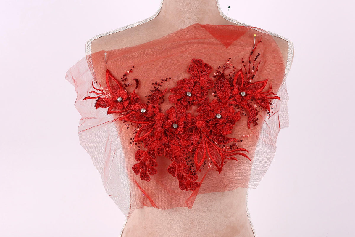 A mannequin wearing a red floral lace overlay on its chest.