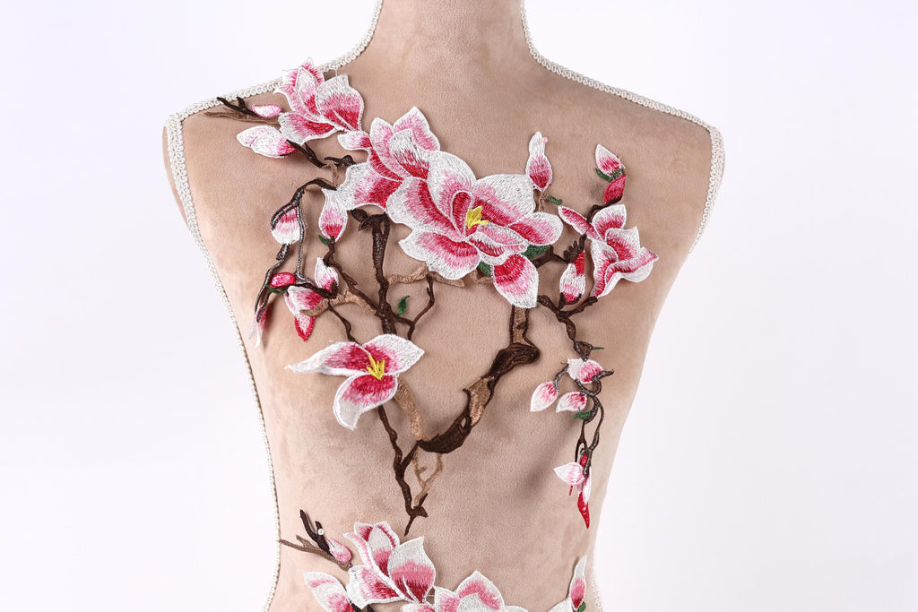 A mannequin torso with a floral embroidered design on it, featuring pink and white flowers and branches.