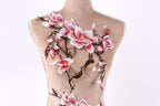 A mannequin torso with a floral embroidered design on it, featuring pink and white flowers and branches.