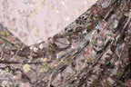 a close-up view of a delicate, intricately embroidered fabric with a floral pattern. The fabric appears to be made of a sheer material, with a variety of colors and designs, including pink, green, and black elements. The image is a close-up of the fabric, focusing on the details and textures of the embroidery.