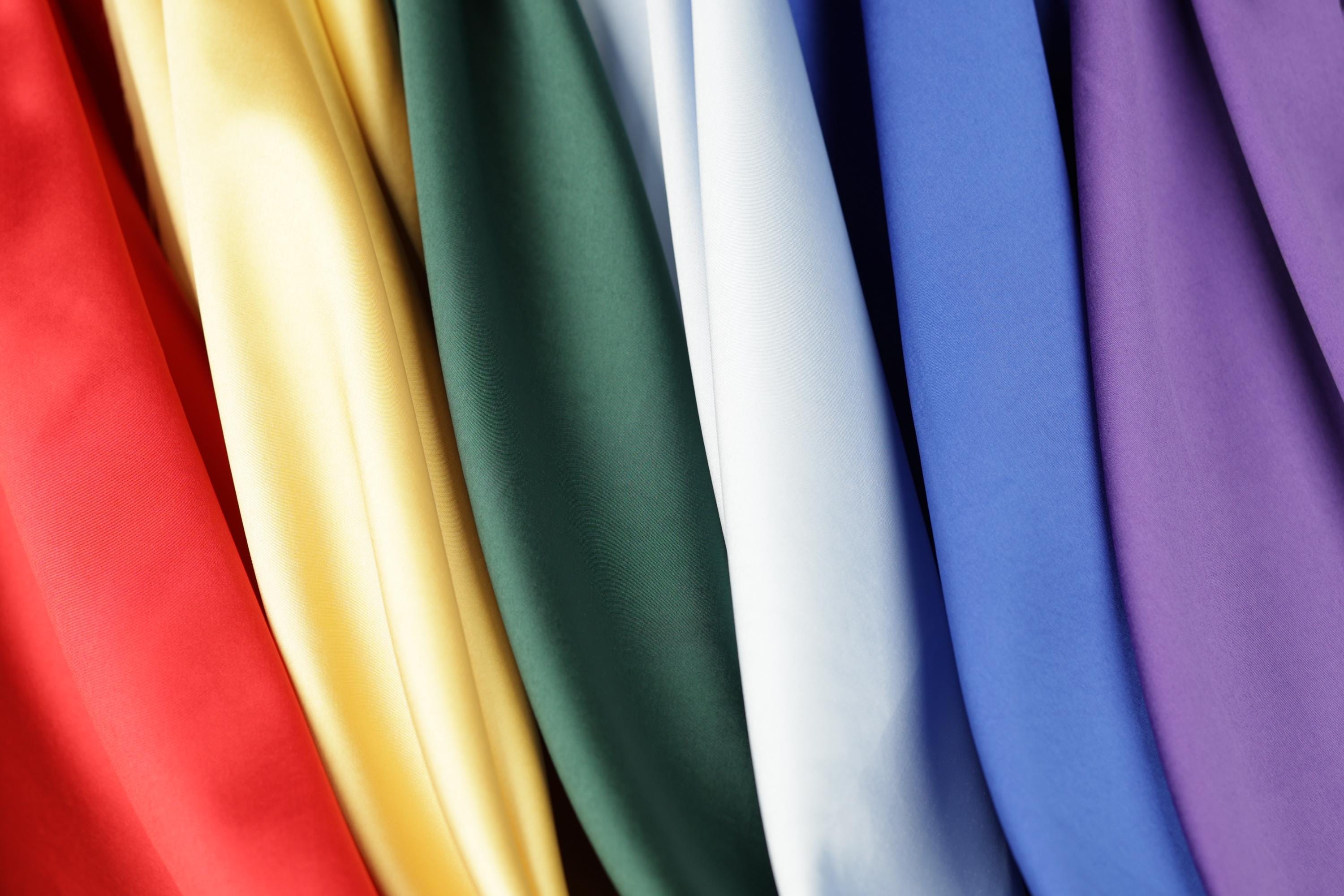 A close-up view of a variety of colorful fabric swatches, including red, yellow, green, white, blue, and purple.